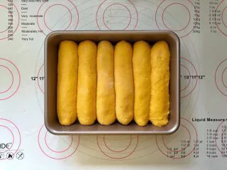 南瓜豆沙排包,14、收口向下码入学厨9寸烤盘中,盖上保鲜膜进行二次发酵。