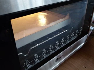 圣诞树根蛋糕,倒入铺了油纸的正方形烤盘里,在桌面上震几下,震出气泡,放入已经预热好上火170度下火175度的东菱烤箱,中下层烘烤18分钟左右