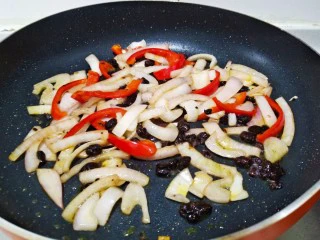 快手正餐 豉香螺旋意面（西餐中做）,热锅倒入少许食用油，油五分熟放如豆豉煸香，然后倒入红椒丝和洋葱丝一起炒15秒。