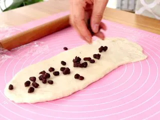 蜜豆吐司 宝宝辅食,翻面，撒上蜜豆 tips：下方面用手压薄一些，有利于卷起吐司卷收口 