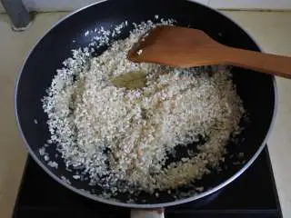 煎南美虾球配意式墨汁海鲜烩饭,大米和一片香叶用橄榄油炒至大米半透明