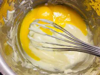 可可波纹戚风蛋糕,加入蛋黄Z字搅拌均匀后,加入香草精华搅拌均匀。