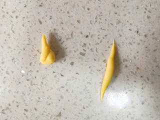 零色素卡通馒头可爱独角兽馒头,取大概1.5g黄色面团搓成如图右边两头尖的形状,然后对折扭麻花一样扭一起。如图左边形状。这样就做好一个独角兽的角了。一共做四个。面团重量只是参考,实际可以随手操作。