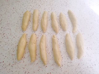 果酱辫子面包,松弛好的面团按扁卷起，搓成长条状。