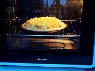 杂蔬火腿肠披萨,放入预热好的烤箱,上下火200度,中层烤15-20分钟,烤至表面芝士融化变成焦黄色即可