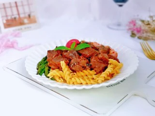 牛排芦笋盖意面,把煮熟的意面装盘,把煎好的牛排切成牛肉粒,盖在意面上。芦笋,香肠一起摆盘,小番茄装饰在上面。