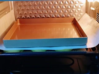 蜜豆喜饼～香甜松软,发酵好的喜饼胚是原来两倍大，盖上一张油纸，再放上一个烤盘。