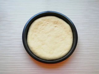 火腿彩蔬披萨,发酵好的面团揉光排气，擀成和披萨盘一般大小的面饼，放入披萨盘里。