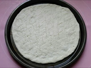 馅料足足的超级至尊匹萨,用叉子在面饼上扎孔