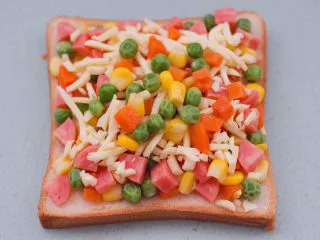 田园时蔬吐司披萨,我在芝士碎上又撒了一些时蔬碎，这样就可以让宝贝多吃一些蔬菜咯。