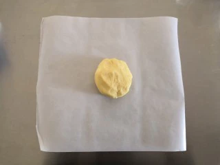 苹果奶酥小挞,混合成面团后取一张油纸将面团放在油纸上。