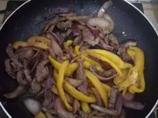 黑椒牛柳意面,等洋葱炒得基本都透明时,彩椒也应该全熟了,倒入牛肉,撒上海盐,黑胡椒末,迷迭香,罗勒叶碎,快速翻炒两下即可