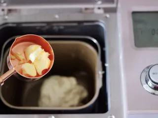 圣诞雪花豆沙包,启动面包机的一个和面程序，一个和面程序以后，看见面团揉至光滑的扩展阶段后开始放入黄油。 