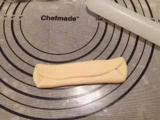 危险与美味并存一一德国碱水包,取1小份面团，擀成椭圆形，1/3对折后再对折