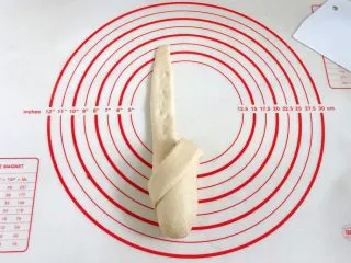 牛奶炼乳蔓越莓软欧,没擀开的部分用手掌轻轻压下,将切开的右边那条面片往左下角方向折。