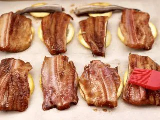 日式柠香烤鳗鱼,把腌制好的鳗鱼平铺在柠檬片上，注意鱼皮要朝下，刷一遍蜂蜜水。