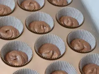 巧克力熔岩杯子蛋糕, 将面糊装入裱花袋中。先在杯子蛋糕纸托中挤一层面糊