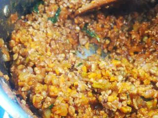 意大利肉酱意粉,煸炒约5分钟后，放入百里香、罗勒叶、红酒继续煸炒。直到红酒完全收干后放入番茄酱，约炒5分钟后放入面粉继续煸炒两分钟（面粉分3次加入，每次都充分搅匀后再继续加入）。最后加入清水（水量已刚末过原料为准），小火熬制15分钟，将盐、鸡精放入肉酱中，盛出待用。