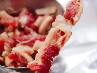 洋葱香烤五花肉,把腌制好的五花肉块，用竹签串起来。