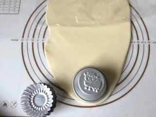 可爱圣诞帽子塔,将面团擀成长方形薄片,取一个圆形模具,刻出圆形面片,圆形模具要比蛋挞模具稍大一点