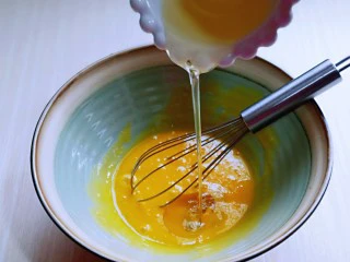 红丝绒草莓奶油蛋糕卷~下午茶必备甜品,先做蛋黄糊,蛋黄用手动打蛋器打散,加入玉米油,使油和蛋液完全融合再一起,(色拉油也可以,但是一定要无味的)不建议使用黄油或橄榄油。
