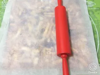 蔓越梅沙琪玛,上面铺上烤盘纸用擀面杖来回擀,一定要压紧,否则切块的时候会松架。