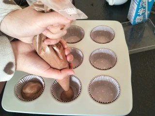 最“柔软”纸杯蛋糕☕—爆浆巧克力,挤入纸杯蛋糕模具。没有这种烤盘的话，也可以用硬纸杯来操作。😊
