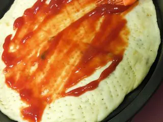 小白也会的奥尔良烤鸡腿披萨 「8寸薄脆版」,这时候我们可以开始放料了。醒发之后的面比刚才更软更蓬松了一点，然后就可以刷番茄酱了，可以刷稍微多一点，味道比较浓。