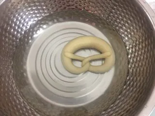 德国碱水面包普雷结,冷冻好后戴手套把面团在碱水中浸泡20秒,反面也泡20秒捞出