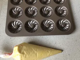 柠檬味小蛋糕,把面糊装入裱花袋！前面剪个小口，挤入模具，9分满