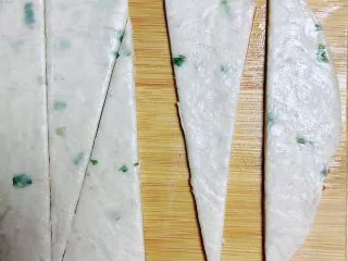 葱油飞饼香肠卷,将葱油味飞饼从冰箱拿出回温，切成等腰三角形。（宽度刚好能放下一根香肠）