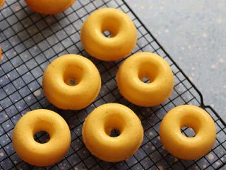 橙味甜甜圈蛋糕，在家就可复刻的经典美味,取出稍微晾一下，就可以用牙签划一下，倒扣脱模了。放到晾网上，晾凉。期间可以准备融化巧克力，蔓越莓干切碎。