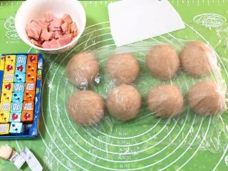 奶油黑麦奶酪包,面团分成八个剂子,盖上保鲜膜静置20分钟,火腿肠切小片,干奶酪和沙拉酱准备好。