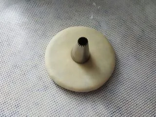 中式点心~玫瑰酥,取一个面胚,擀成圆形,中间用裱花嘴做一个圆形的记号。