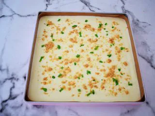 香葱肉松蛋糕卷,烤盘铺上耐高温油布，再把蛋糕糊倒入烤盘中，表面用刮刀抹平，提出烤盘震一震，震出大气泡，再撒上葱花和肉松