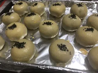酥到掉渣的豆沙蛋黄酥,你要来一个吗?,刷蛋液,撒黑芝麻。放入预热好的烤箱,上下火180度烤25-30分钟即可。