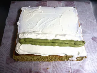 丸久小山园名物蛋糕卷--抹茶,夹馅:将蛋糕体毛巾面朝上,抹上一层甜奶油,近端的甜奶油抹厚点,然后挤上抹茶奶油,再盖上甜奶油。