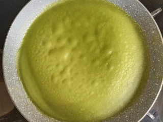 抹茶千层蛋糕,取个平底不粘锅,舀入一勺面糊,转一圈摊平,小火煎到表面冒泡,取出饼皮放凉备用。