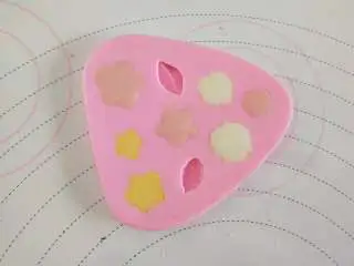 女巫杯子蛋糕,白巧克力隔水融化,分出一小部分加一滴色素做花心用!硅胶膜花心的部分挤一滴粉色巧克力,然后用白巧克力填满!做出帽子上的小花