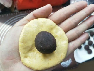 南瓜糯米夹心饼,取一块面团按压扁。包入豆沙馅