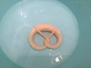 危险与美味并存一一德国碱水包,准备一个塑料盆，先倒入40度温水，再倒入烘焙碱，带上塑胶手套（一定要），将普雷结放入碱水内，泡10－20秒后翻面再泡10－20秒，捞出沥干水分