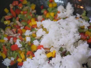 蔬菜虾仁焗饭,把米饭加入翻炒好的蔬菜中翻拌均匀