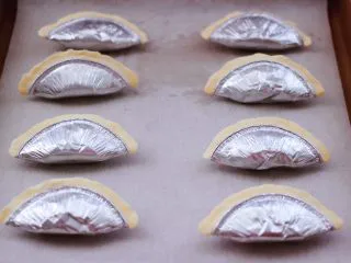 草莓芝士酥～蛋挞皮版,依次做完所有的蛋挞皮，烤盘上铺一张油纸，把做好的草莓芝士酥，放入烤盘中。