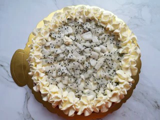 红丝绒水果裸蛋糕,抹上一层奶油,放上小块的火龙果,用裱花袋里的奶油在蛋糕边上挤出奶油花。