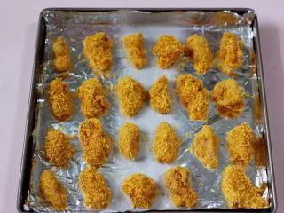 少油减脂的劲爆鸡米花,做好鸡胸肉放在垫有锡纸的烤盘，静置10分钟，这样面包糠就会和鸡块融入在一起，不会掉渣渣了。