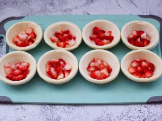 草莓芝士酥～蛋挞皮版,看见蛋挞皮软化以后，把切丁的草莓均匀的放到蛋挞皮里。