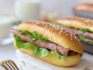 胡萝卜热狗面包,做营养美味早餐,面包体腰切开,或者是顶部切开,放入蔬菜和火腿,挤上色拉酱、番茄酱,一个美味的热狗面包就完成了。