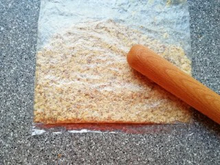 芝麻核桃一口酥,核桃仁装进保鲜袋,用擀面杖压碎。