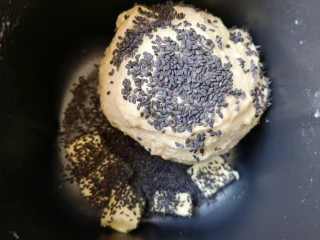 麦片芝麻小餐包,15分钟和面程序结束以后放入软化的黄油和熟黑芝麻,继续选择面包机的“自动和面”15分钟。