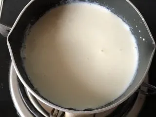 免烤❗️芒果酸奶蛋糕,牛奶用小火加热，吉利丁冷水泡软后挤干水，放入牛奶中，搅拌均匀！ 